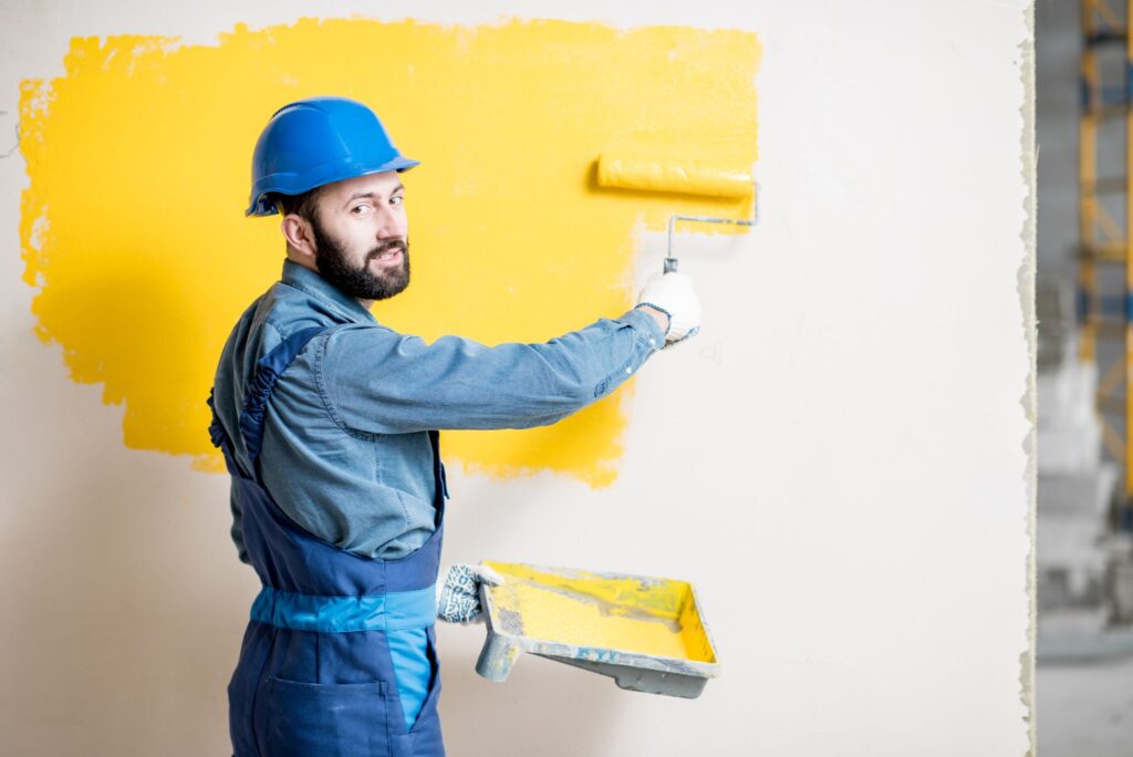 a person painting a wall with yellow paint